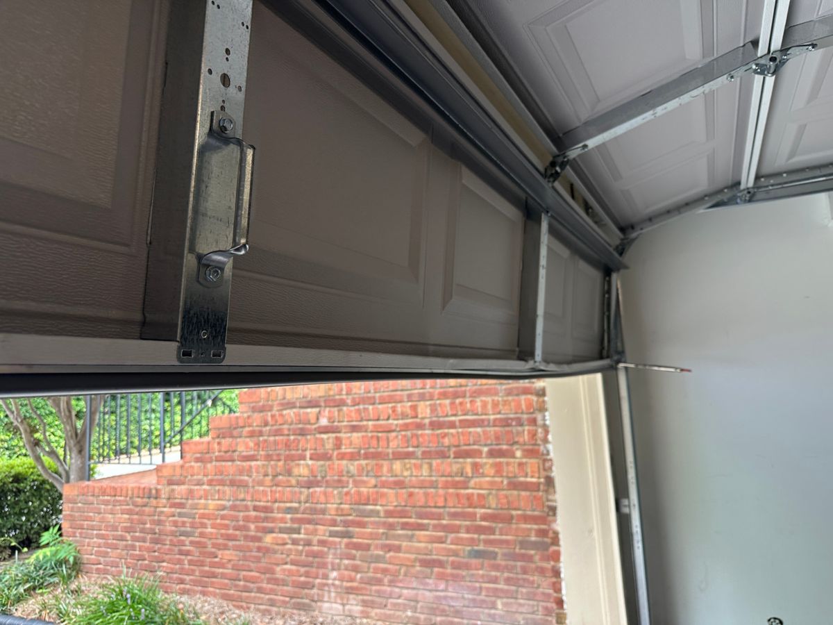 The garage door repaired and back on its track, with rollers seated correctly and the sections aligned, after service in Tucker Georgia