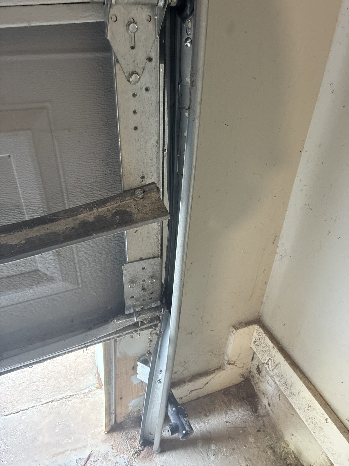 Close-up of the bent and damaged vertical garage door track pulled away from the jamb in Decatur, Georgia