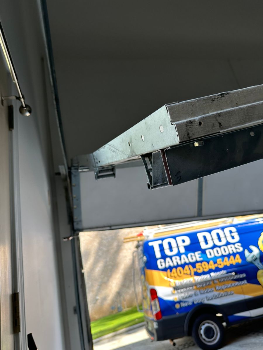 Bent garage door track and torn hardware pulled away from the jamb during a damage assessment in Atlanta