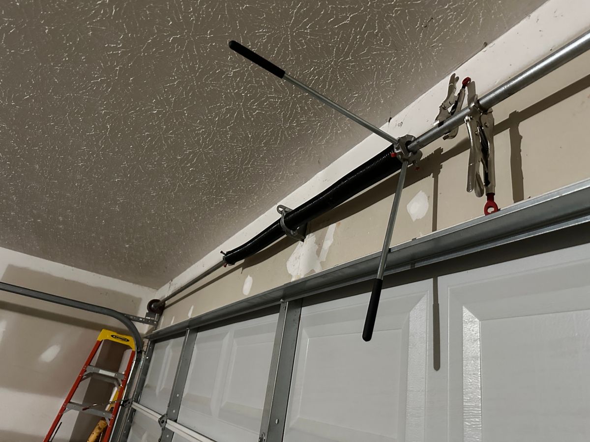 New garage door spring being installed and wound with winding bars during a spring replacement in Stone Mountain, Georgia