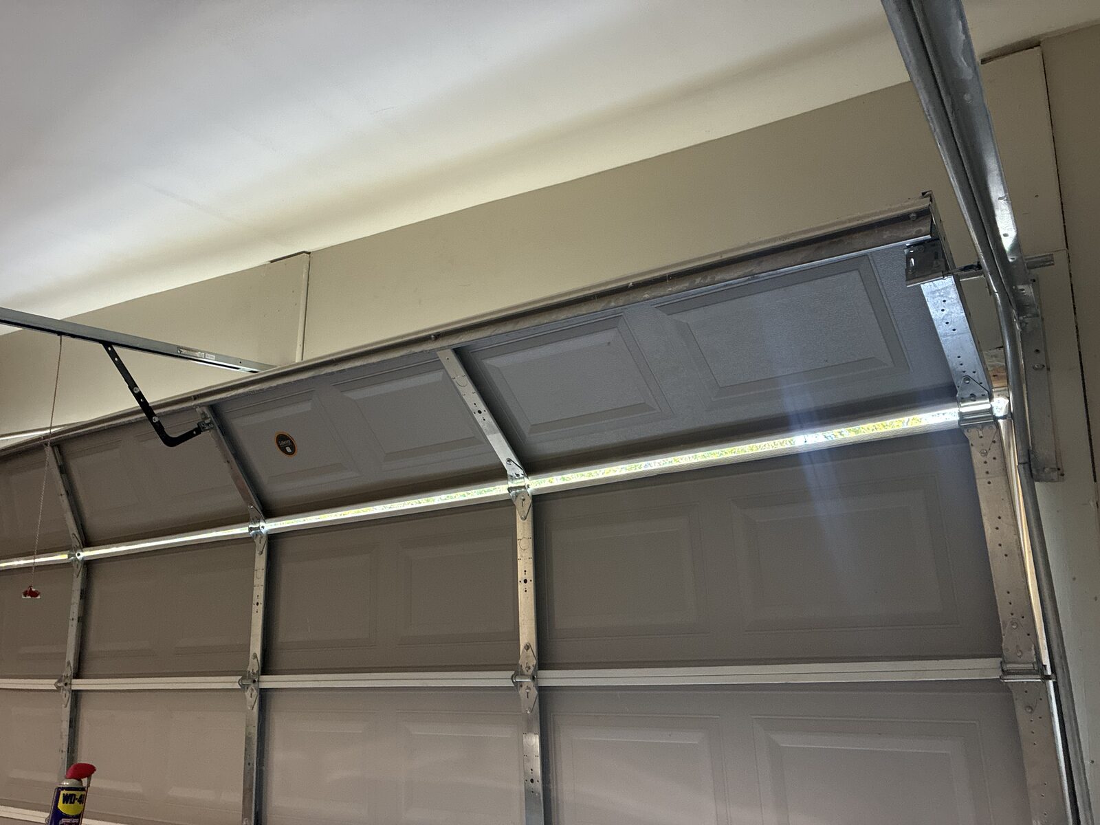 Garage door off its track and hanging dangerously from the top section inside a Decatur, Georgia garage