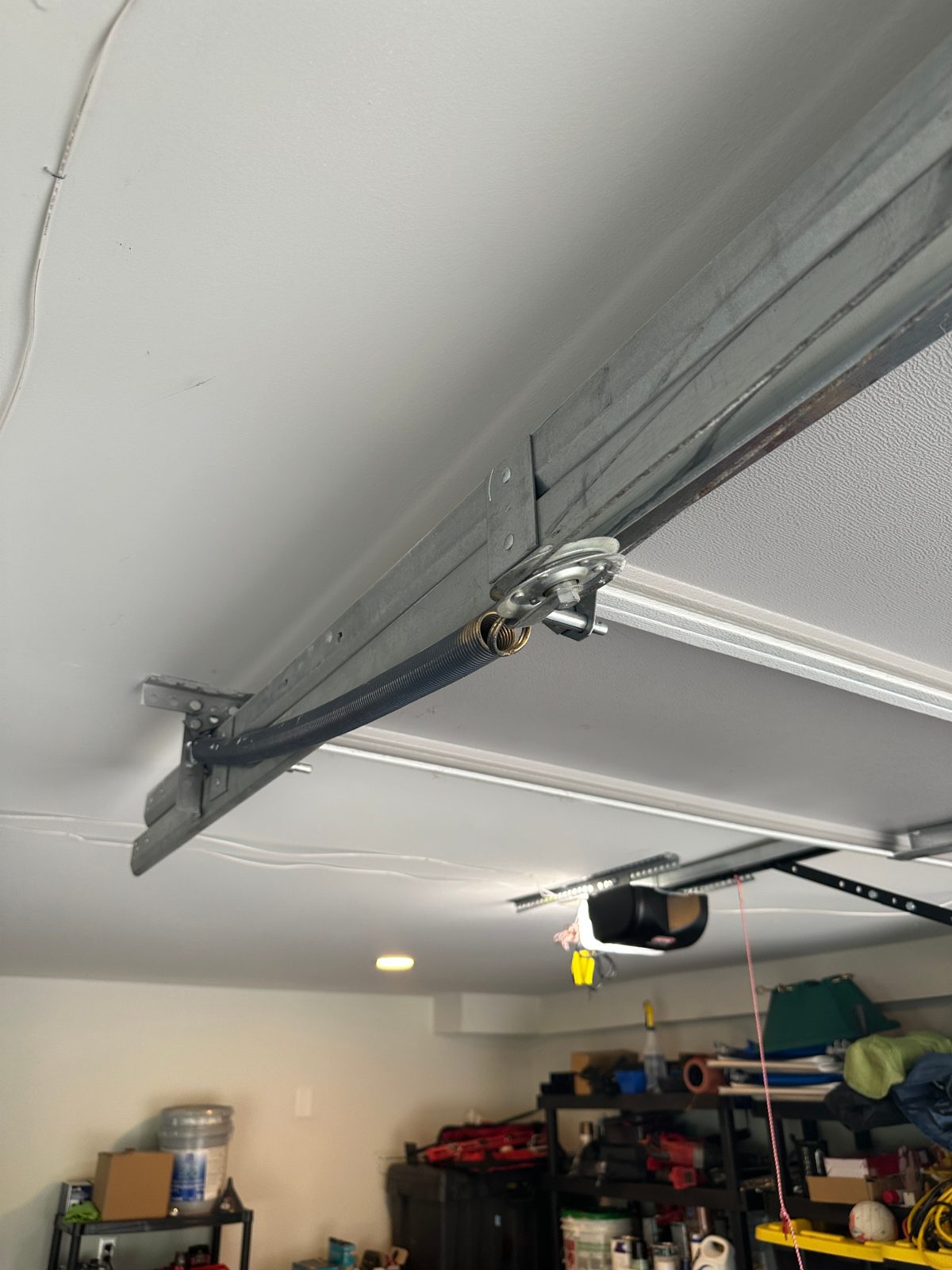 Extension spring on a residential garage door track in Dunwoody, GA, shown without a safety cable running through it