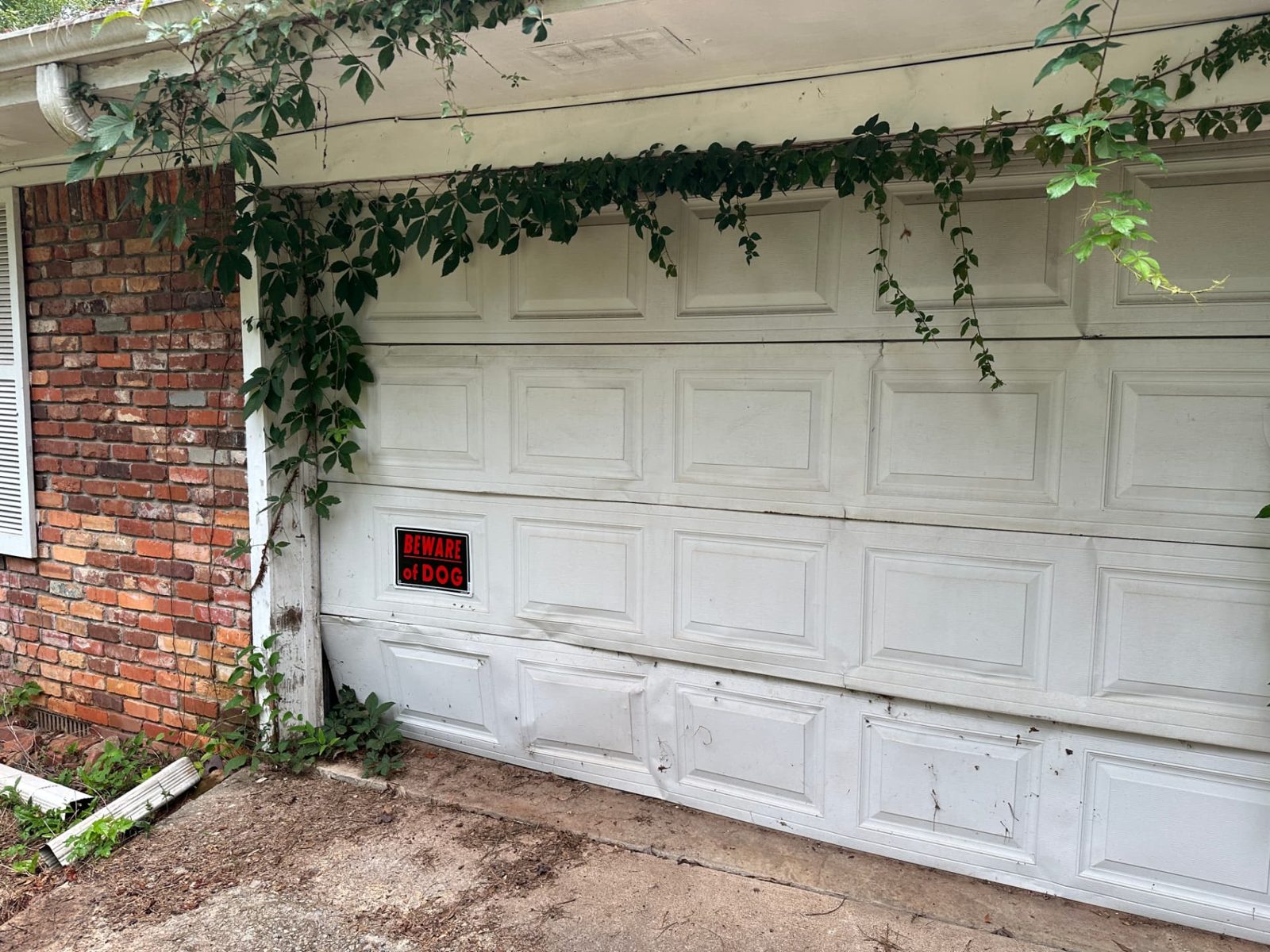 Garage door with severely damaged panels being assessed for replacement in Decatur, Georgia