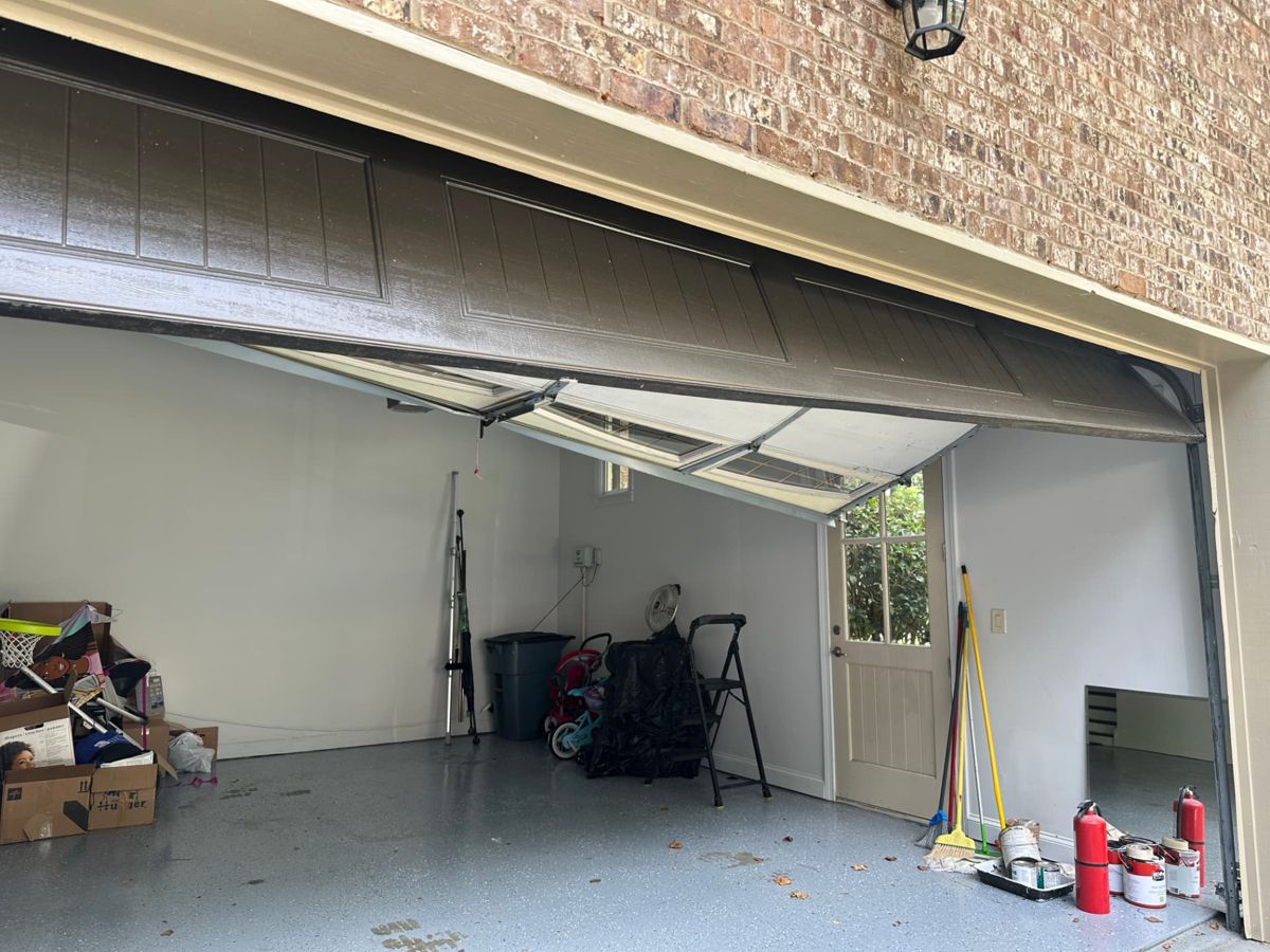 Crushed and bent garage door panels and window section sagging out of alignment in an Atlanta garage